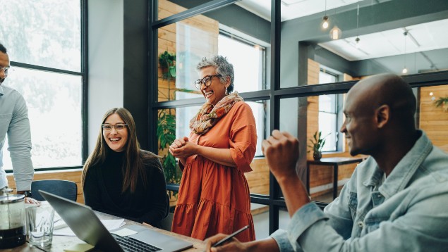 Group of office workers laughing around a conference table