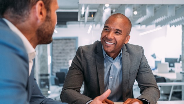 Two business leaders smiling and meeting at a conference table