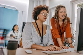 Two safety professional women looking at a desktop computer at the office