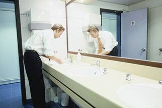 Businessman-washing-hands-in-workplace-bathroom
