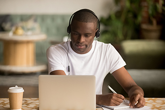 Safety-professional-wearing-headphones-watching-webinar-taking-notes