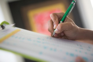 Safety professional man’s hand checking items off a list he has on his green clipboard 