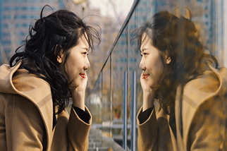 Woman looking at her mirror image in glass.