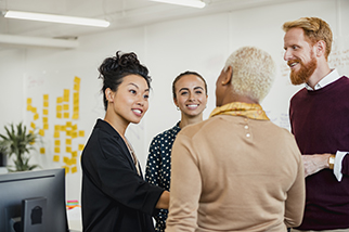 Brainstorming as a Group - Colleagues standing in a small group discussing something while working at an office.