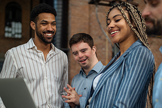 Cheerful young businesspeople with laptop working in office, social inclusion and cooperation concept