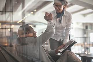 Young businessman and businesswoman giving each other a high five in a modern office space