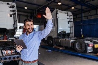 Safety officer in the workplace standing in front of trucks and waving