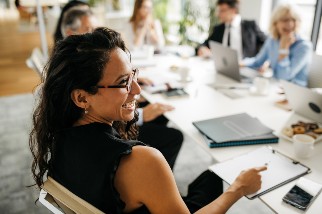 Safety professional woman with glasses sitting in a meeting with colleagues laughing